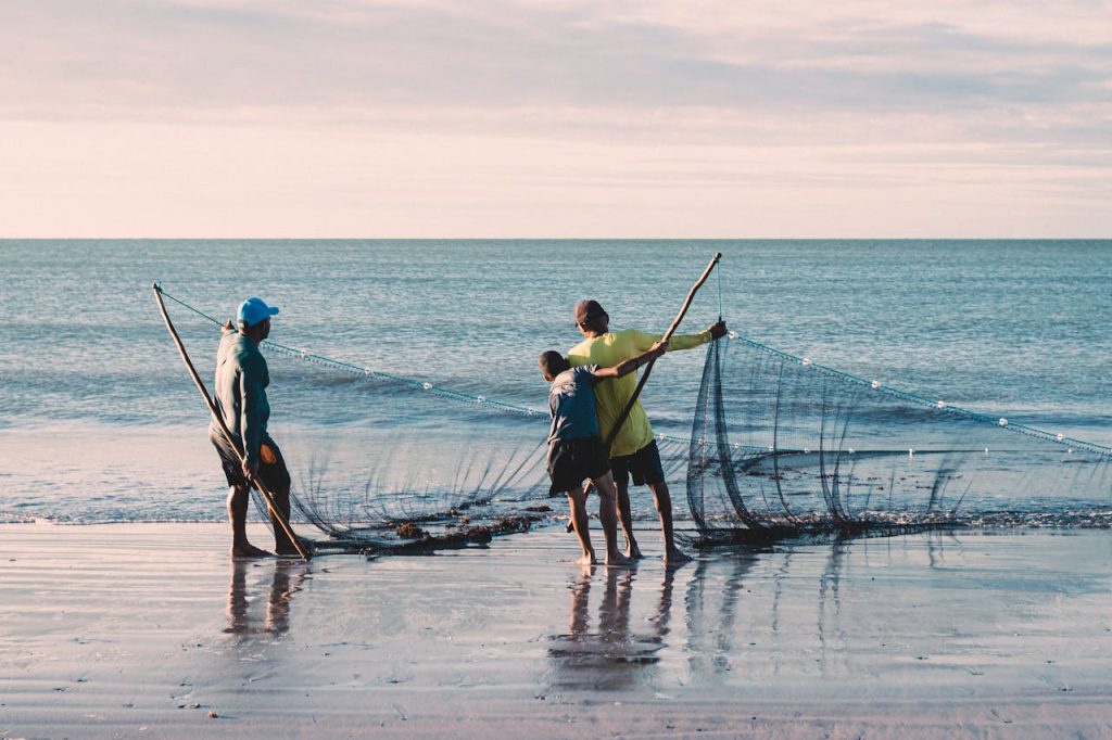 Fishermen with nets at João Pessoa beach in Brazil during sunset.